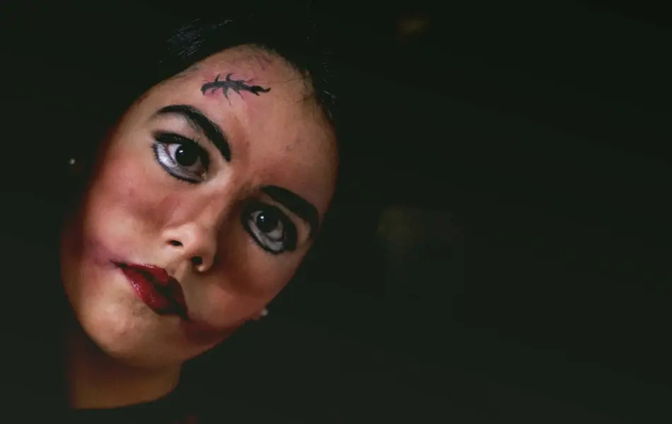 Dame i mørkt rom med skummel sminke