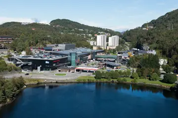 Oversiktsbilde av Sartor Storsenter, mellom vann og fjell i pent sommervær