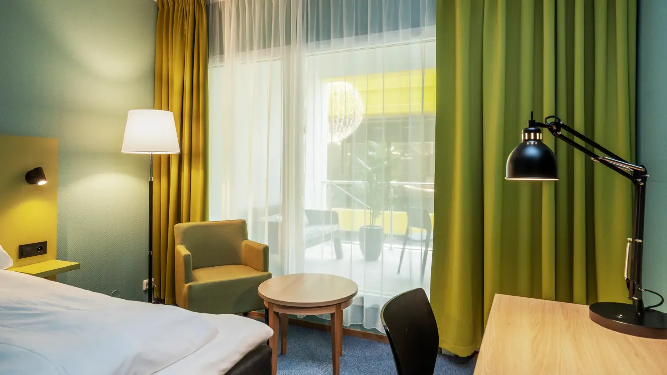 Vindu, gule gardiner, salongbord, lenestol, skrivebord, twin beds, turkise vegger, gulvlampe, svart stol