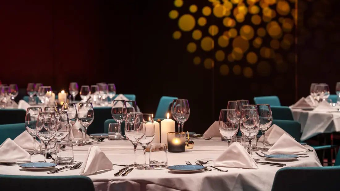 Kveldsstemning, bankett, runde bord med hvite duker og stearinlys. Turkise stoler.
