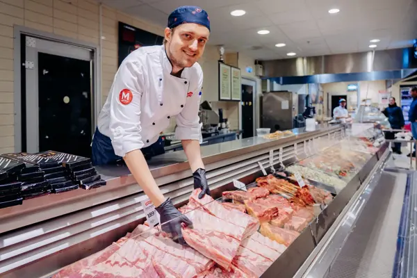 ansatt viser frem fersk kjøtt i ferskvaredisk