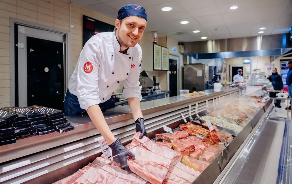 ansatt viser frem fersk kjøtt i ferskvaredisk