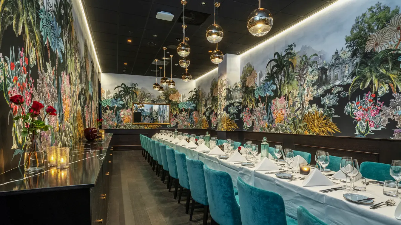 Chabre separée hos Thon Hotel Storo, med langbord dekket med hvite duker og servietter, bestikk, glass og lys, turkise velurstoler, mønstrete tapen, pendellamper med glasskule, avlasningsbord langs langvegg, pyntet med roser og lys. Parkettgulv. 