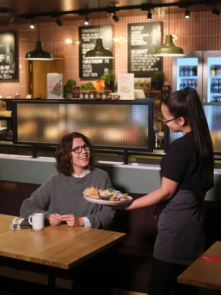 dame får servert mat hos jordbærpikene