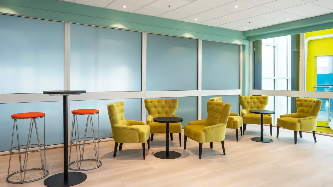 Pauseområde, gule lenestoler, salongbord, vindu, parkettgulv