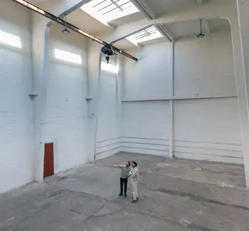 Interiør fra stort, hvitt lagerlokale med to mennesker på gulvet i midten