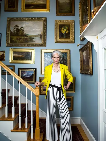 Dame i trapp med vegg full av oljemalerier