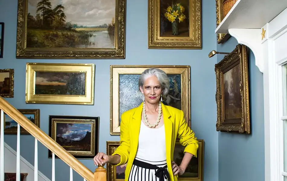 Dame i trapp med vegg full av oljemalerier