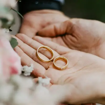 Hender som holder to gifteringer i gull