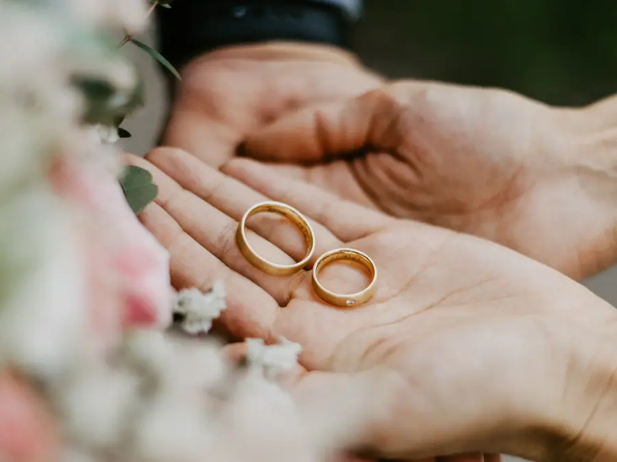 Hender som holder to gifteringer i gull