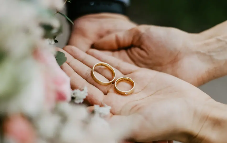 Hender som holder to gifteringer i gull
