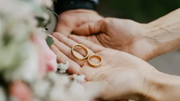 Hender som holder to gifteringer i gull