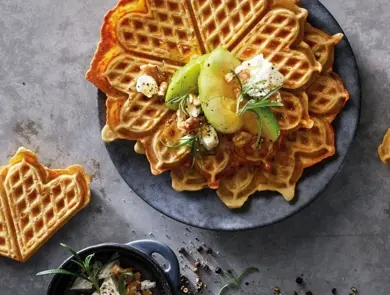 Vafler på grå tallerken, topping av pære, krem og urter