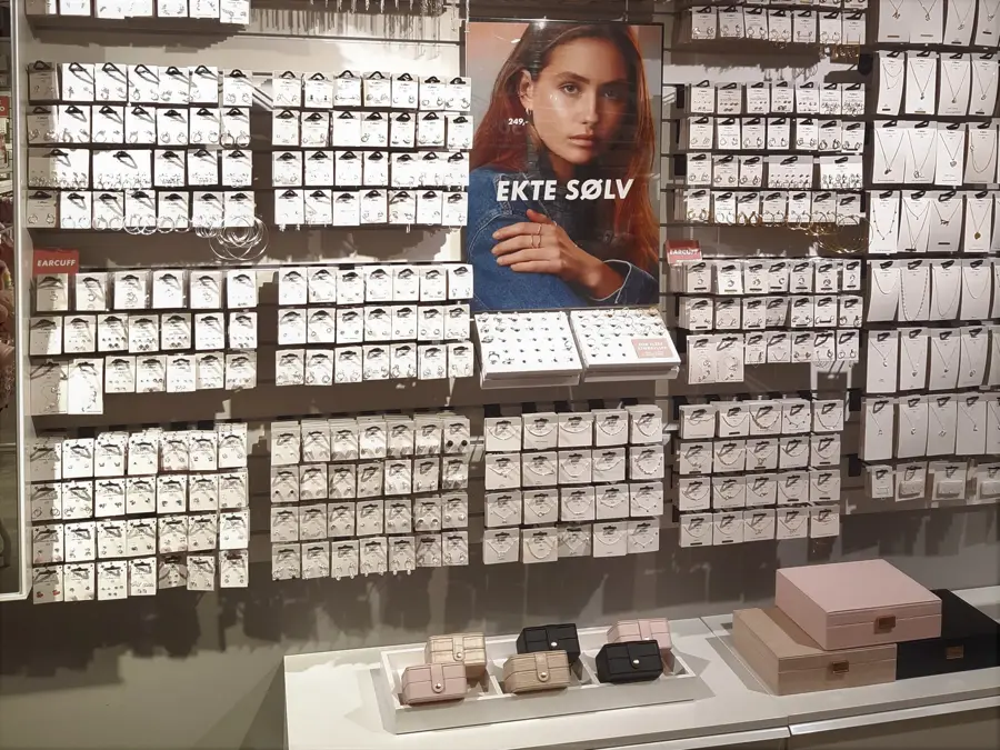 Vegg med en mengde sølvsmykker og bilde av en dame med blå skjorte