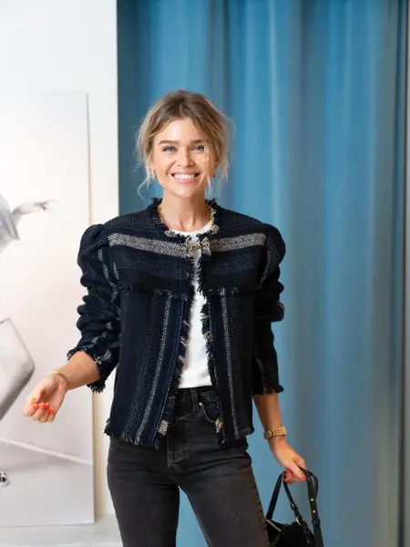 Ung kvinne som poserer i trendy antrekk mens hun smiler mot kamera