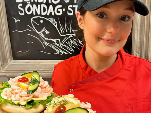 En tjej i röd rock håller i en räkmacka