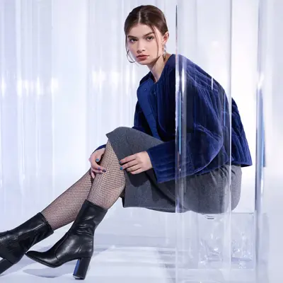 En kvinne i blå genser og skjørt sitter og ser inn i kameraet