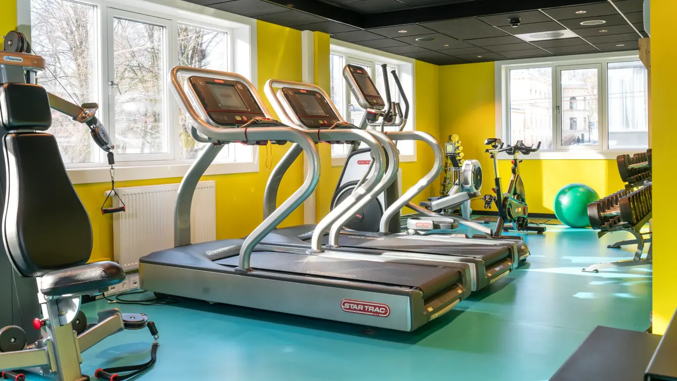Treningsrom med forskjellige treningsapparater med gule vegger og turkis gulv på Thon Hotel Europa i Oslo sentrum rett ved Slottsparken