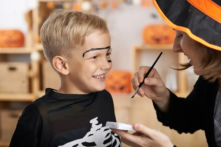 Mother painting face of her son for Halloween celebration