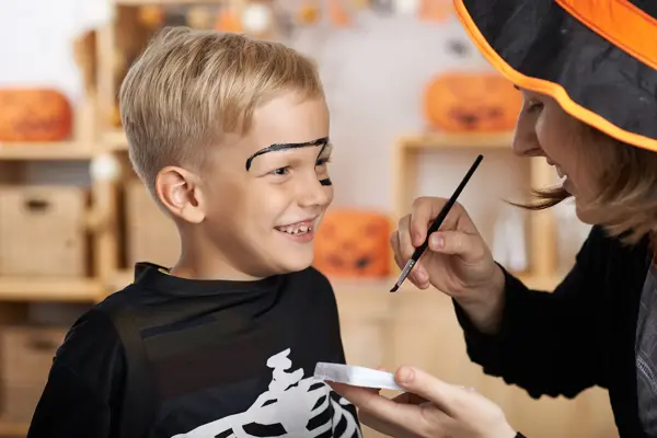 Mother painting face of her son for Halloween celebration
