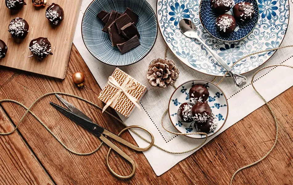 Bord sett ovenfra som er dekket med konfekt og innpakningspapir. Foto.
