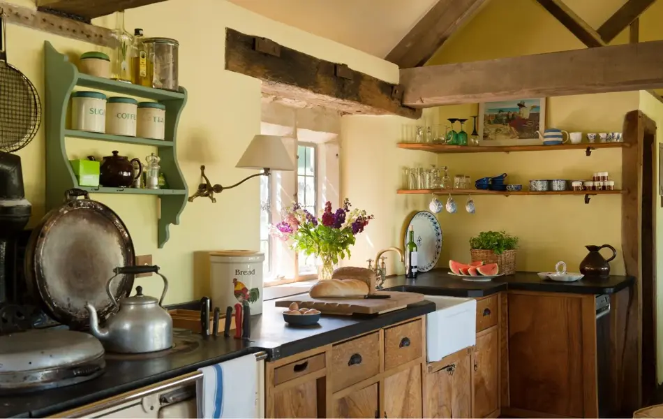 Bonderomantisk kjøkken i oker med forskjellig keramikk, tekanne og friske blomster