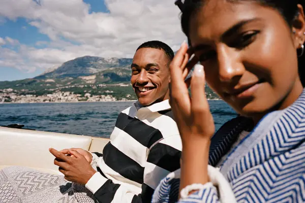 Mann med stripete genser smiler sittende bak hente i båt