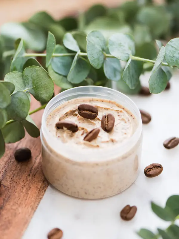 Natural body coffee scrub with eucalyptus branches on marble background. Cosmetic product or face cream container. Flat lay, top view