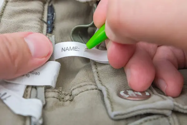 Man fills the Name label on children's jeans.
