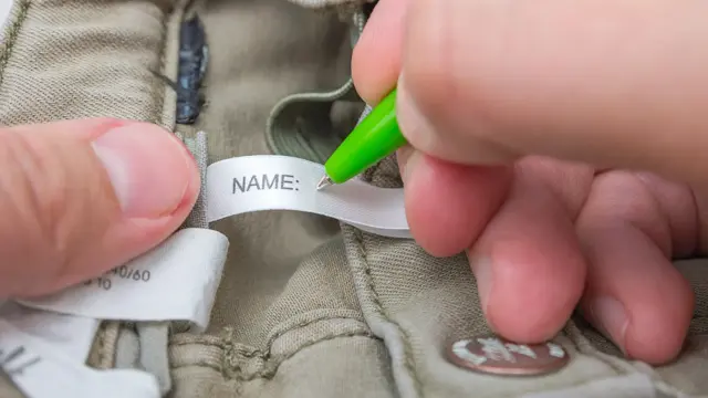 Man fills the Name label on children's jeans.
