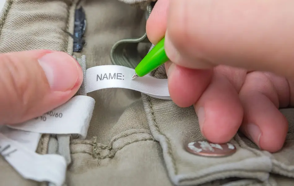 Man fills the Name label on children's jeans.