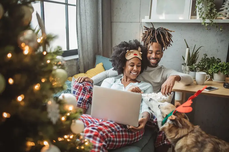 Par og hund ser på film i en julepyntet stue 