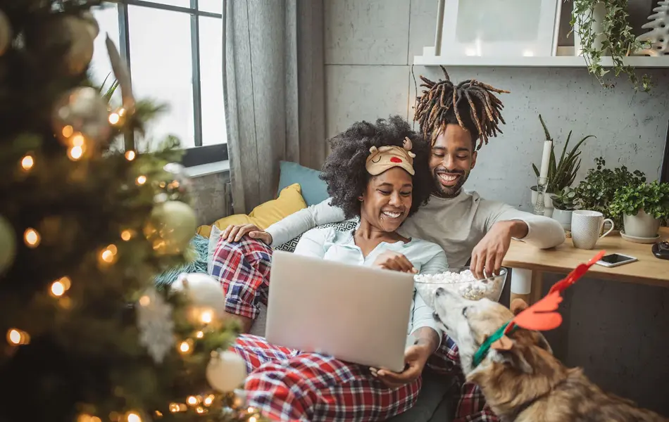 Par og hund ser på film i en julepyntet stue 