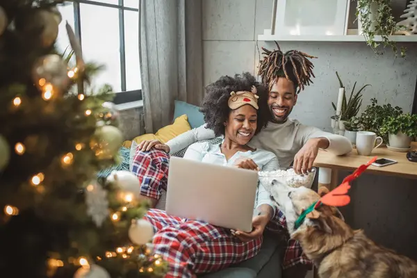 Par og hund ser på film i en julepyntet stue 