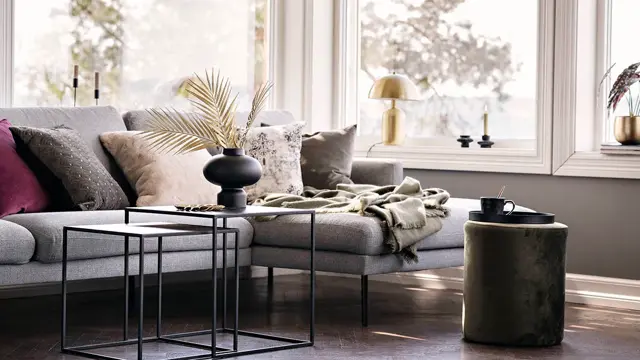 Sofa med puter og sort vase med strå