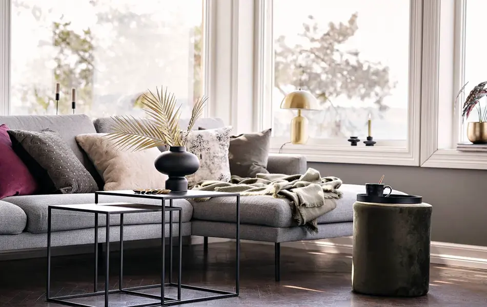 Sofa med puter og sort vase med strå