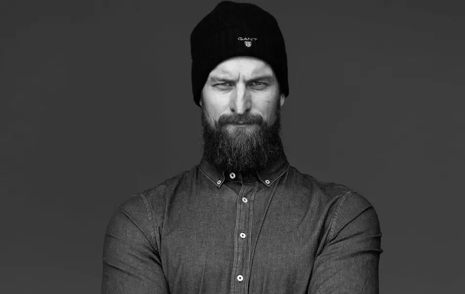 Ung mann med skjegg poserer foran kamera