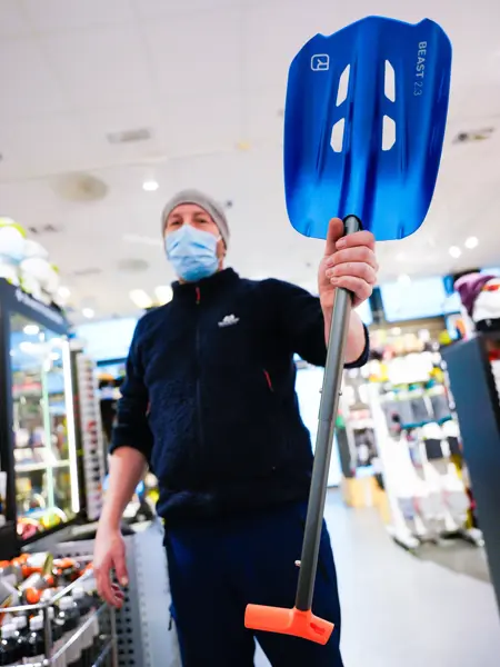 Jente med orangesekk og blådunjakke, og langrennski og slalåmski