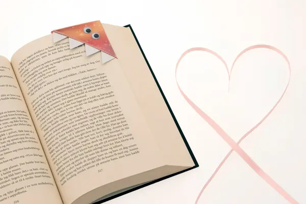 Bok med hjemmelaget "monster"bokmerke og et hjerte ved siden