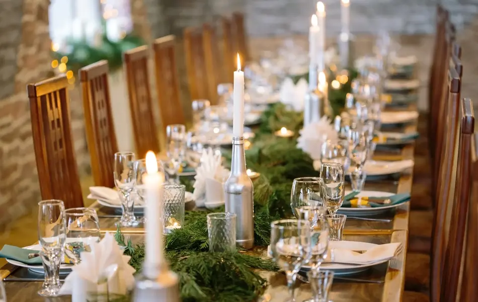 nature, winter, table setting concept. among clean plates, sparkling glasses, candle holders and other silverware there is lots of fresh and aromatic branches of some fur tree