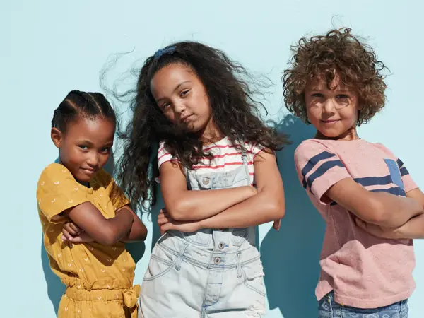 Children having joyful interaction, shot on a blue solid background on the beach in full sun