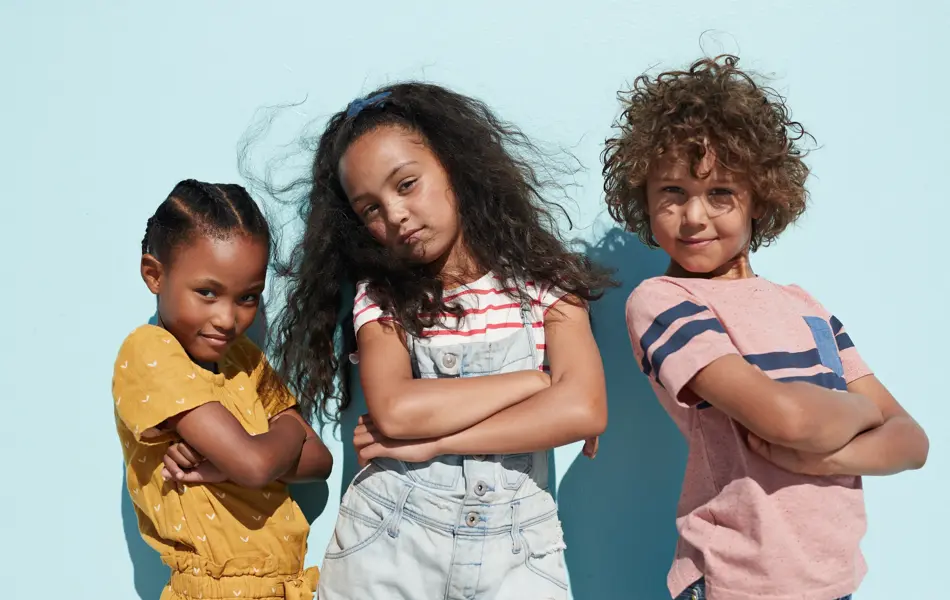 Children having joyful interaction, shot on a blue solid background on the beach in full sun