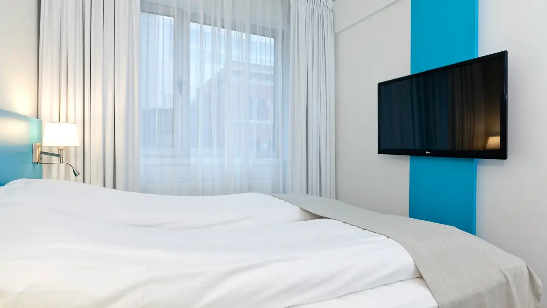 Seng og TV i dobbeltrom på Thon Hotel Munch