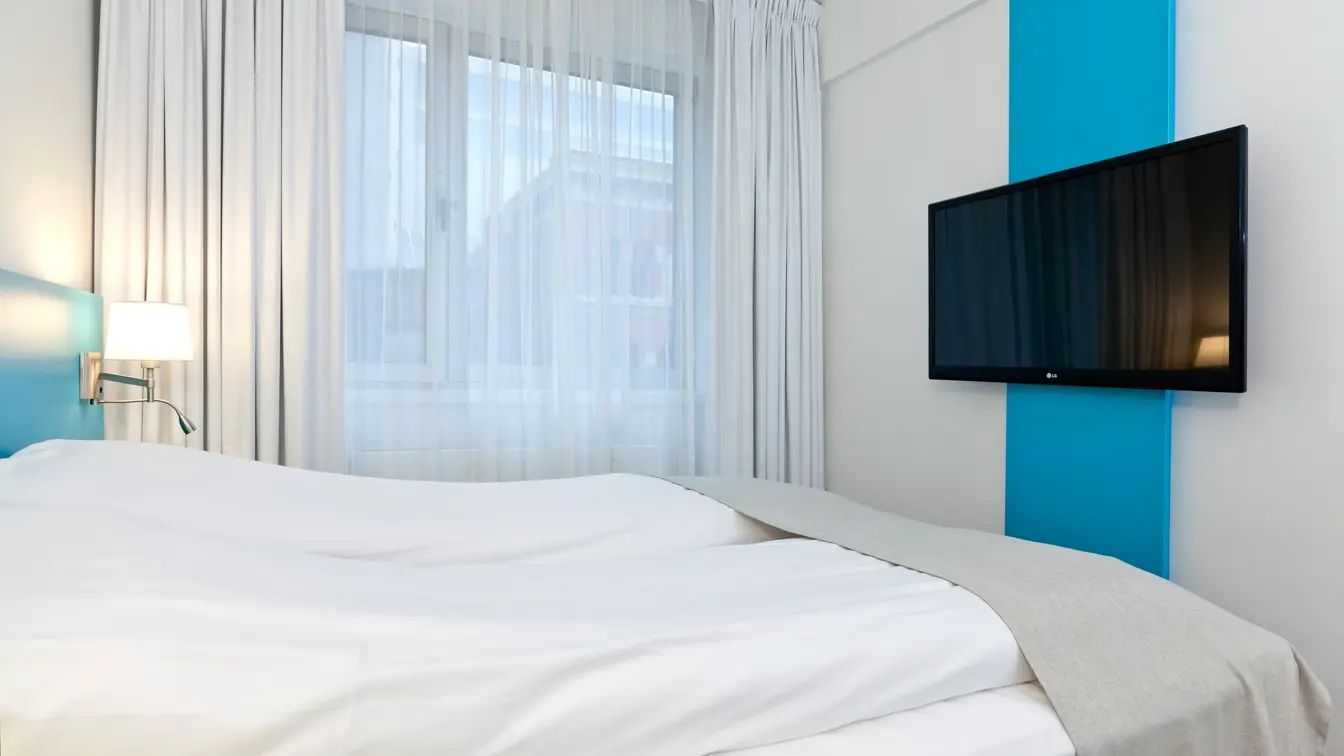 Seng og TV i dobbeltrom på Thon Hotel Munch