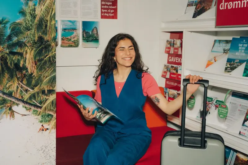 Jente på reisebyrå med koffert