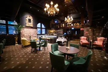 Teppegulv, grupper med runde bord og fargerike stoler, lysekroner i tak