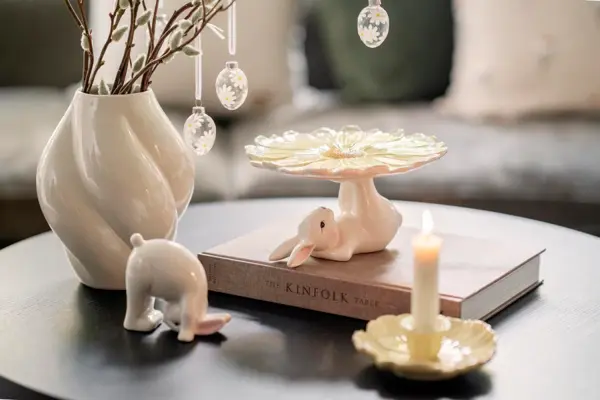 Stuebord med vase med grener og glassegg. Liten kaninfigur, kaninfat og lysestake.