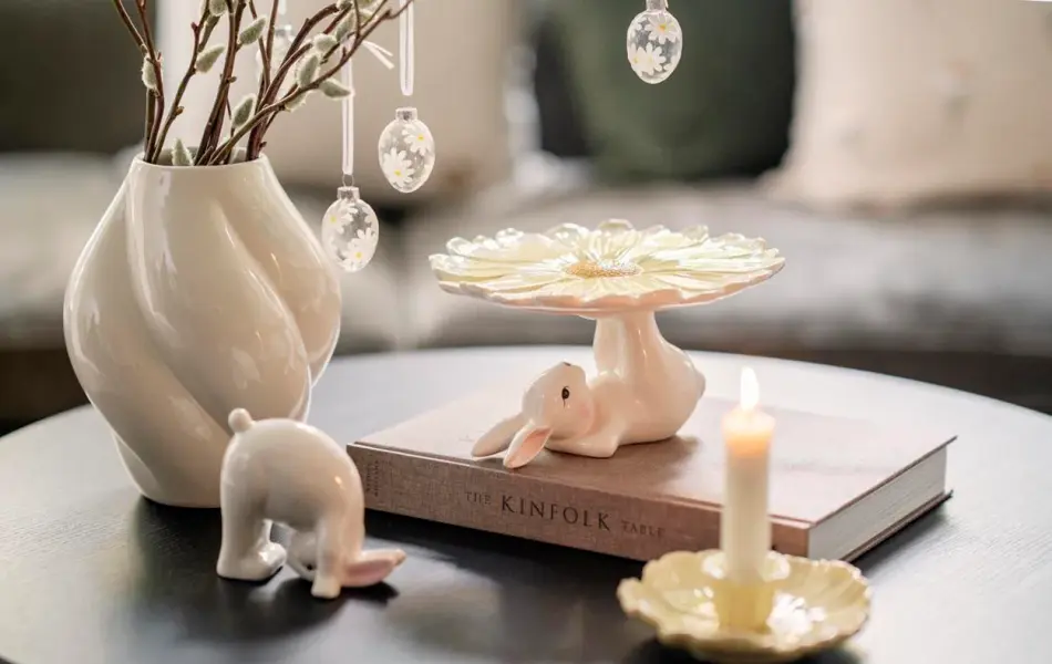 Stuebord med vase med grener og glassegg. Liten kaninfigur, kaninfat og lysestake.