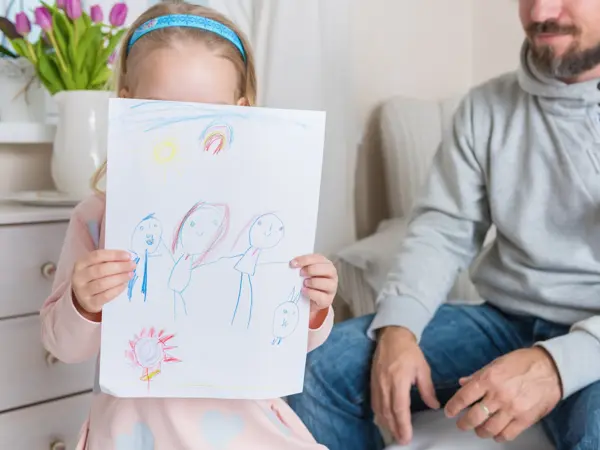 Cute blond girl giving her father a drawing, fathers day concept