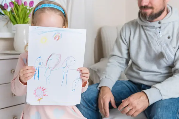 Cute blond girl giving her father a drawing, fathers day concept